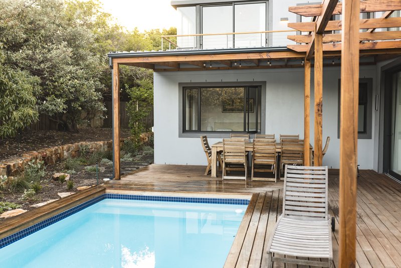 Patio exterior con muebles de madera y piscina.